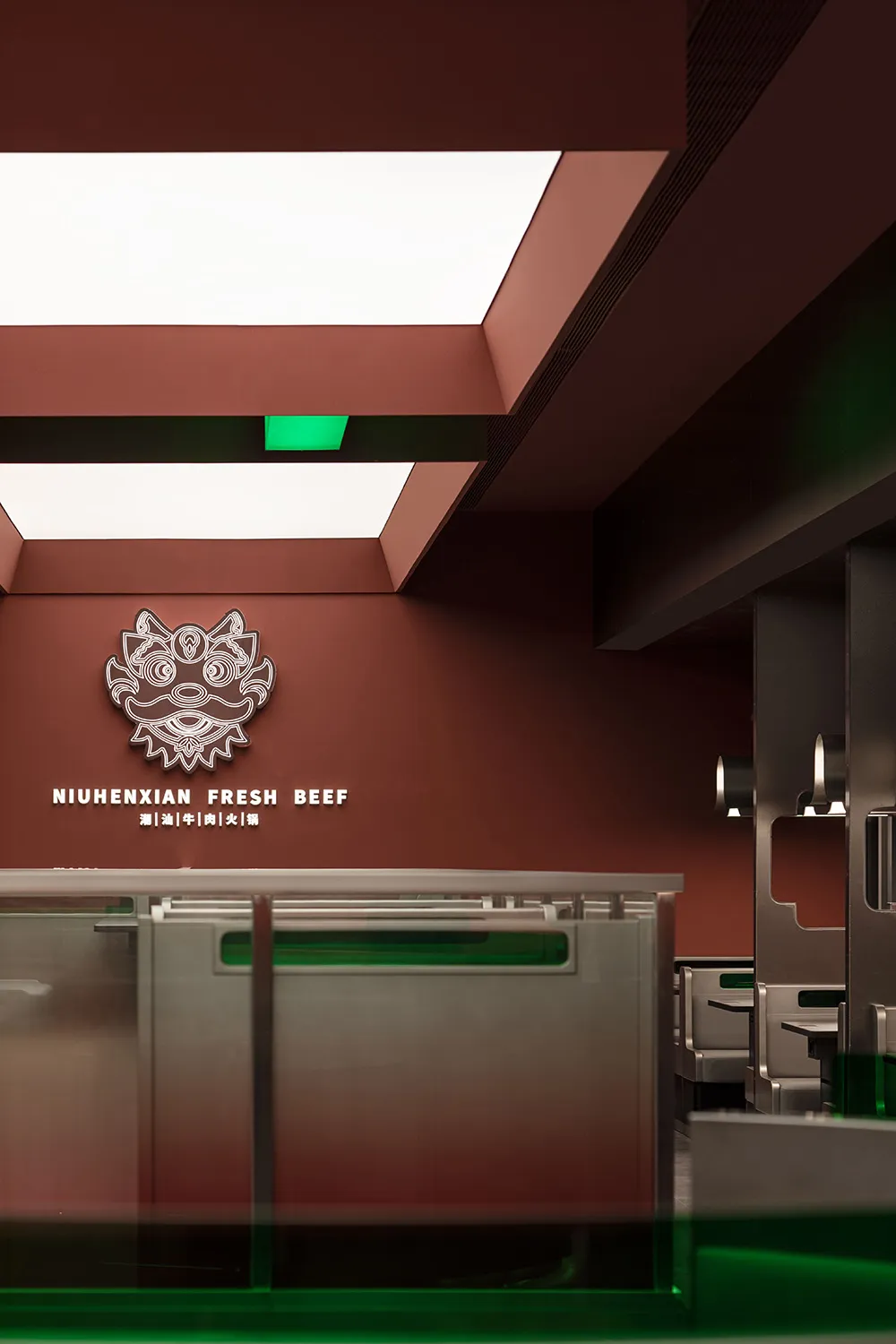 A modern restaurant interior with a red wall, green ceiling, and a counter with a logo, featuring two sinks and a refrigerator in a warm and inviting atmosphere