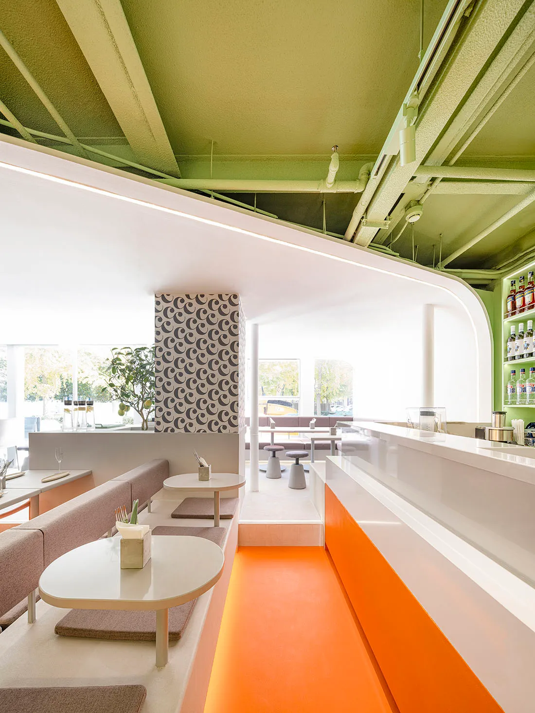 Modern restaurant interior with a bar area, dining table, and chairs, featuring white and orange elements, potted plants, and a warm ambiance