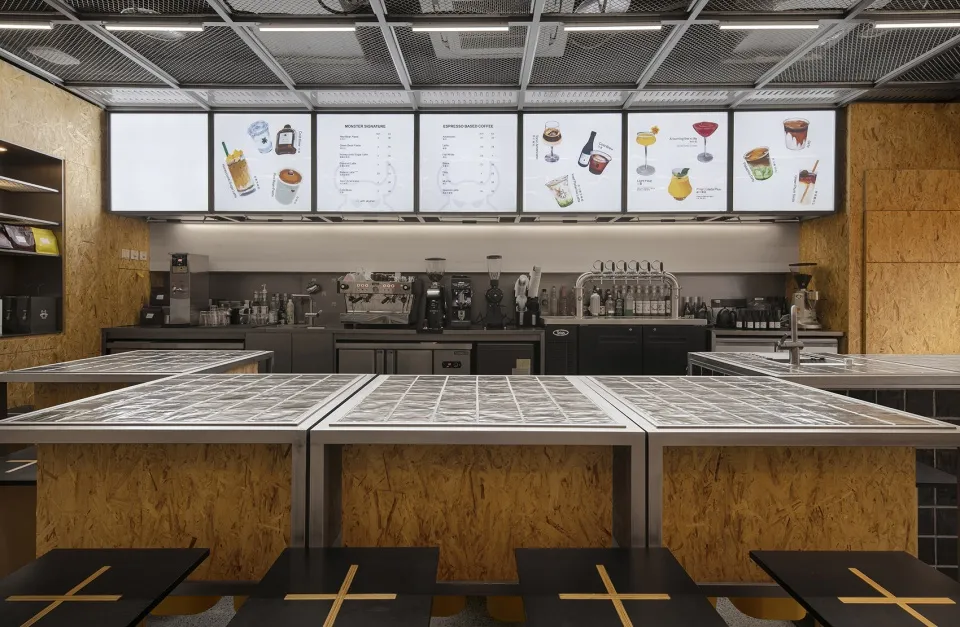 Industrial kitchen with multiple tables, chairs, and appliances, featuring functional and organized spaces for food preparation and serving