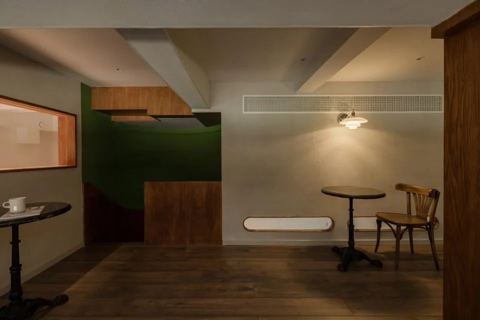 Dining area with a wooden floor, a table, and two chairs, accompanied by a couch near the left wall