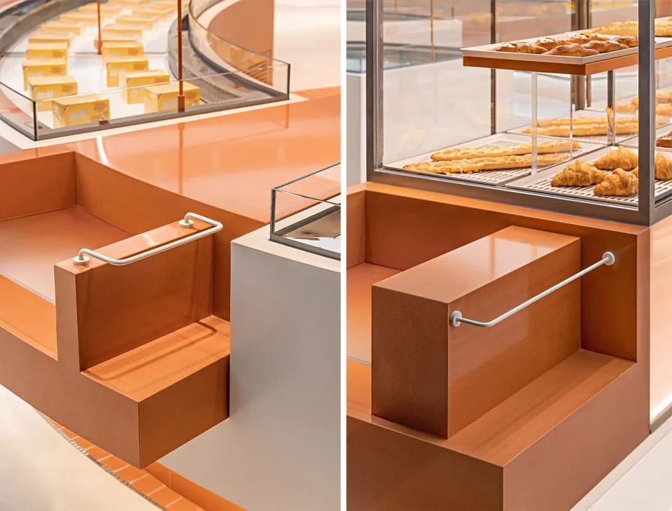 A kitchen with two countertops, one orange and one brown, featuring step-like designs and donuts and bottles on display