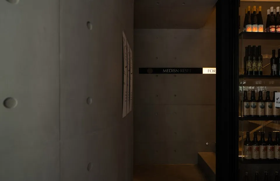 A functional hotel hallway with a white-painted concrete wall, featuring signs and a well-organized atmosphere