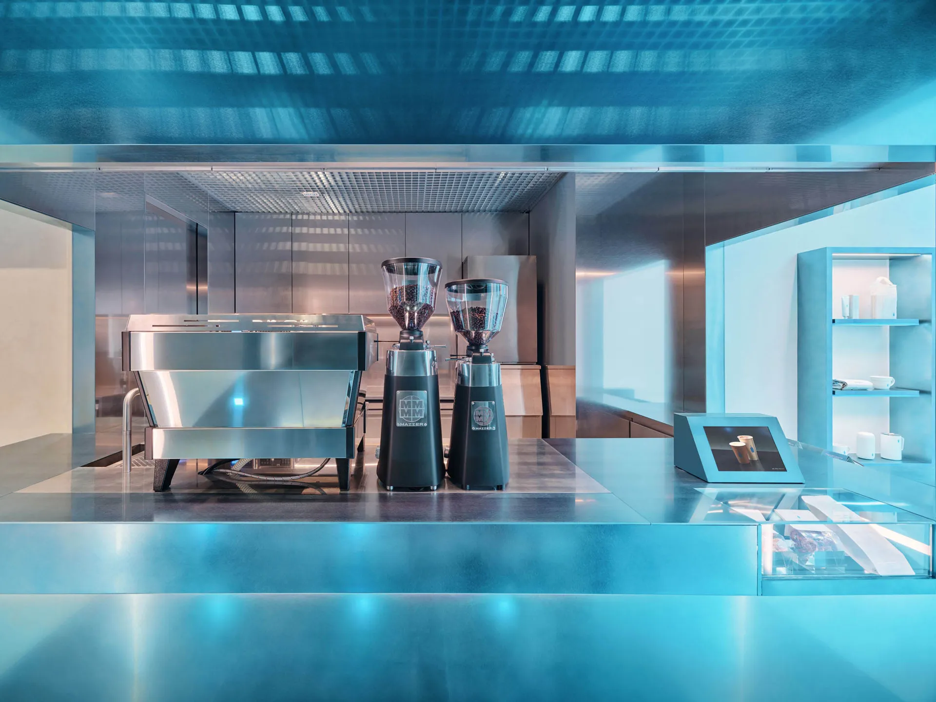 Well-lit modern kitchen with a silver coffee maker, black blenders, and natural light from windows