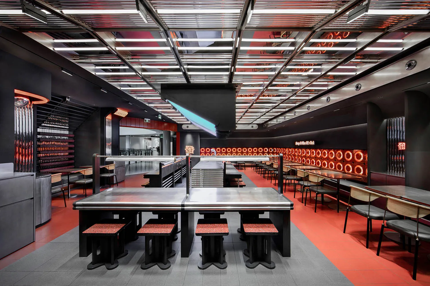 Industrial kitchen dining space with a large dining table, multiple chairs, and benches, featuring a functional and practical atmosphere