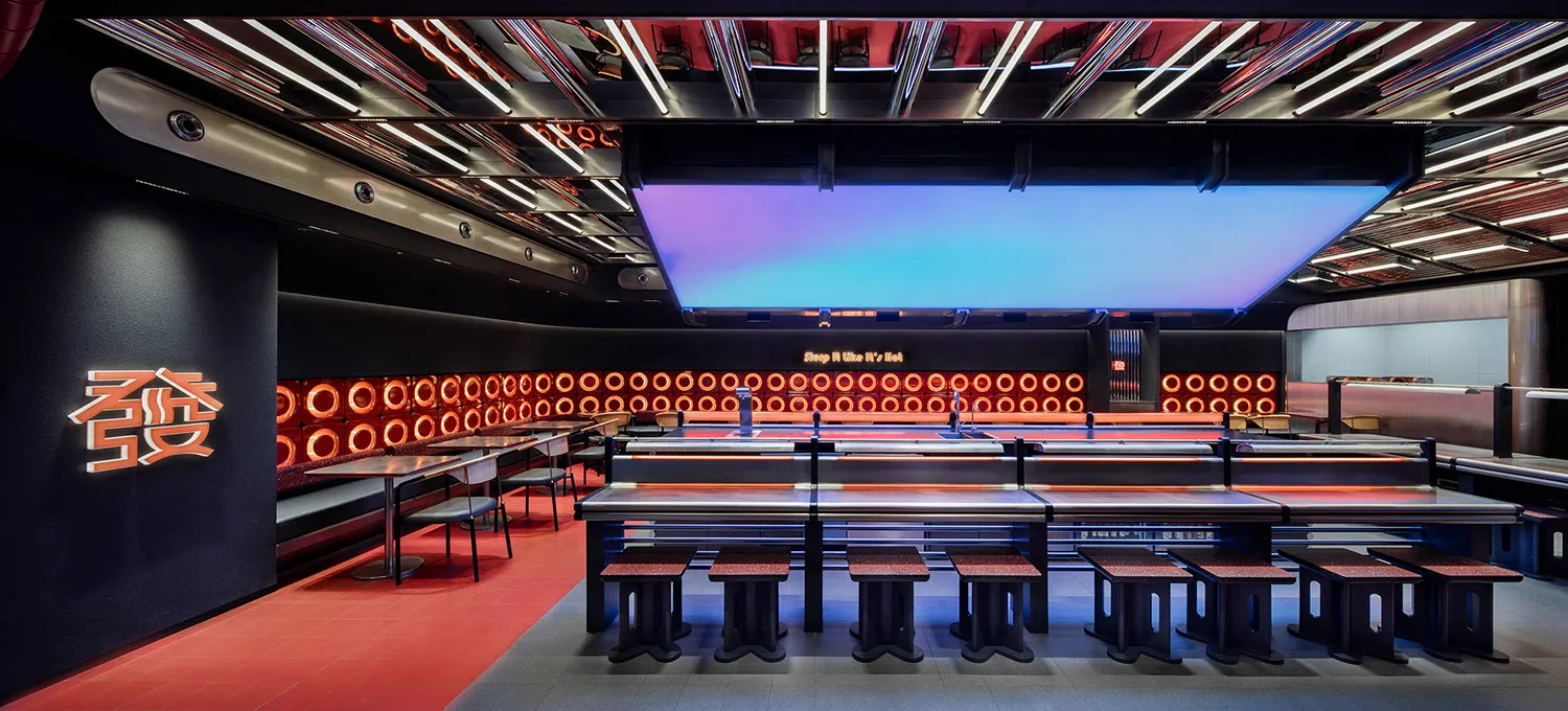 A modern dining area with rows of tables and chairs, featuring a sleek black and red color scheme, creating an inviting atmosphere for meals and socializing