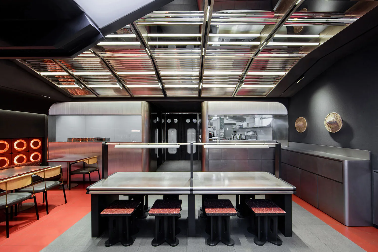 Industrial kitchen with metal tables, black chairs, and commercial appliances, creating a functional and stylish space for events or gatherings