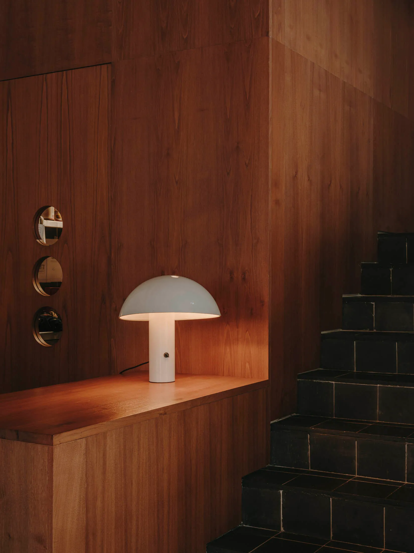 A warm and inviting interior space with a wooden table and a unique globe-shaped lamp, surrounded by cozy wooden elements
