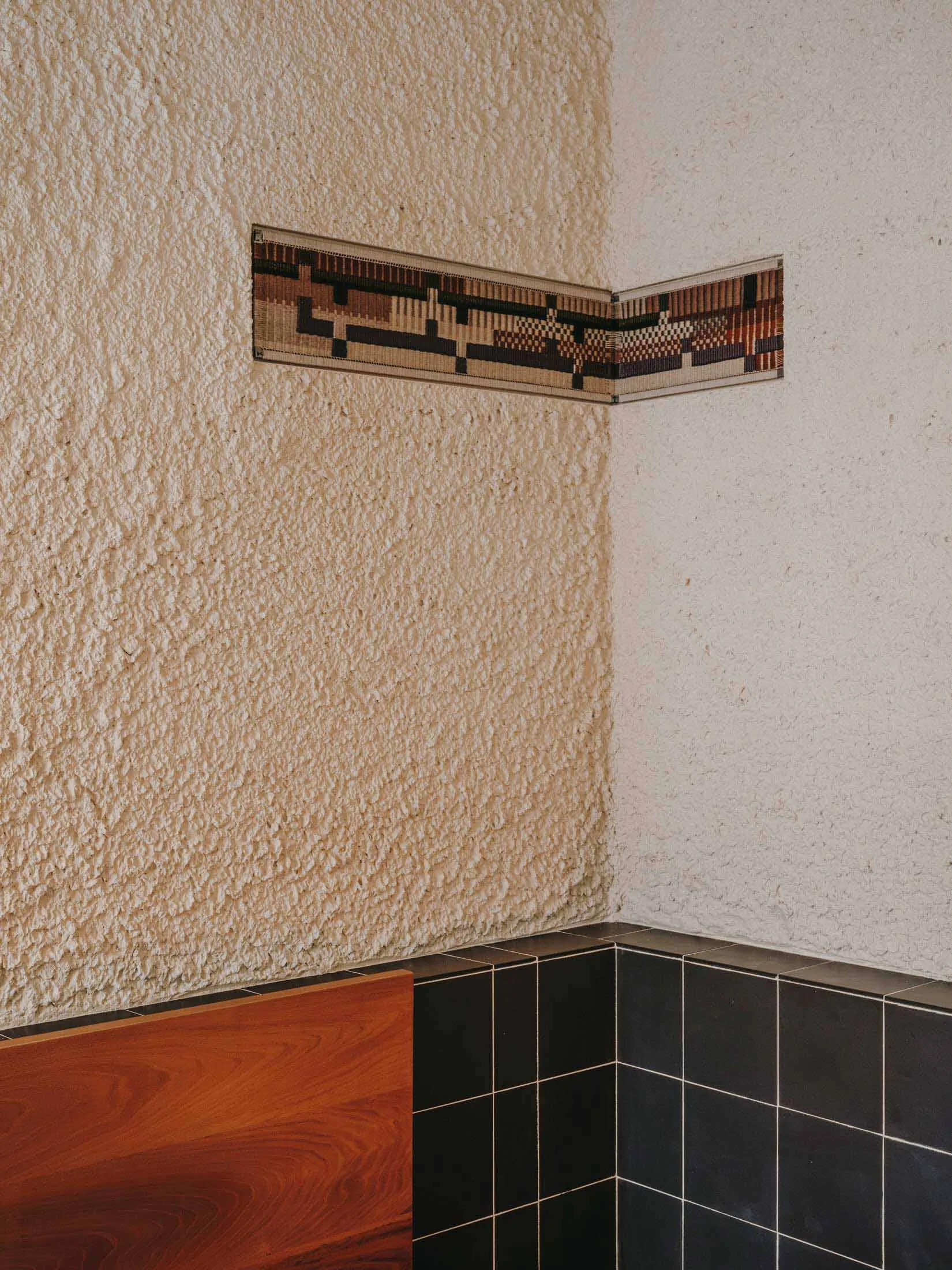 a wooden bench in front of a black and white tiled backsplash in a modern and stylish interior design