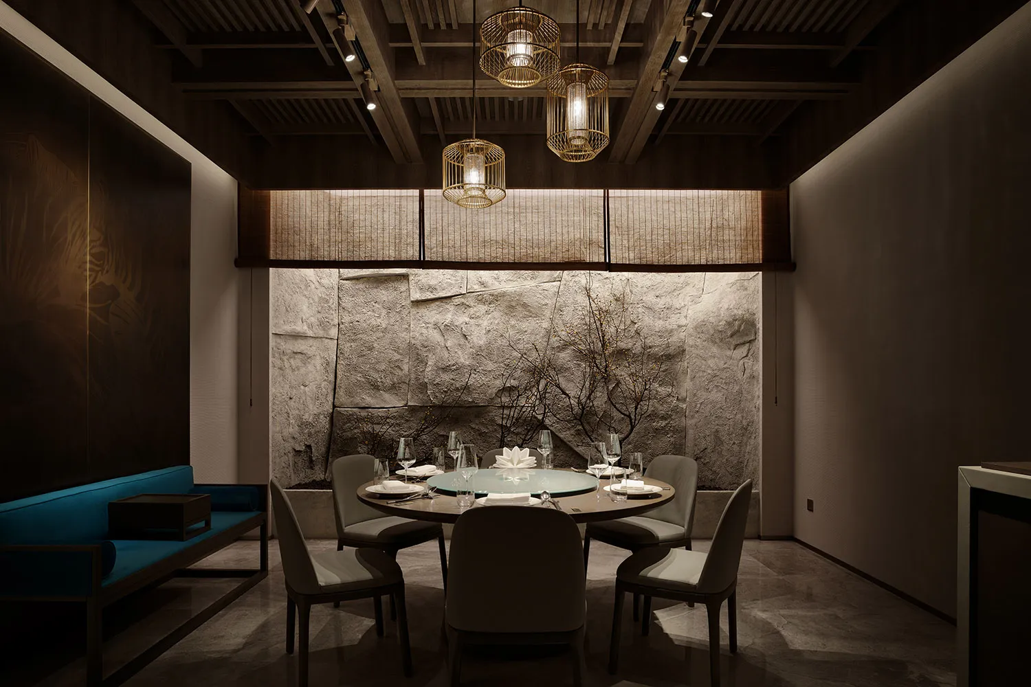 Dining area with a round table, stone walls, and fine china and wine glasses