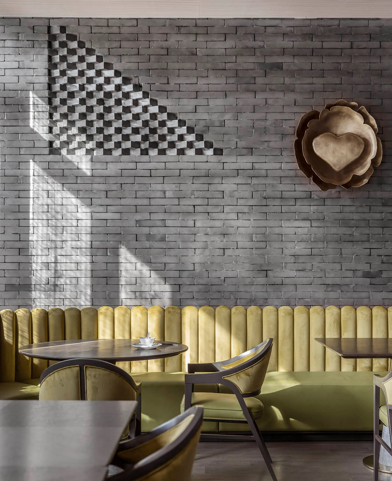 A restaurant interior with yellow walls, grey floors, and various chairs around dining tables, creating a cozy atmosphere with good lighting