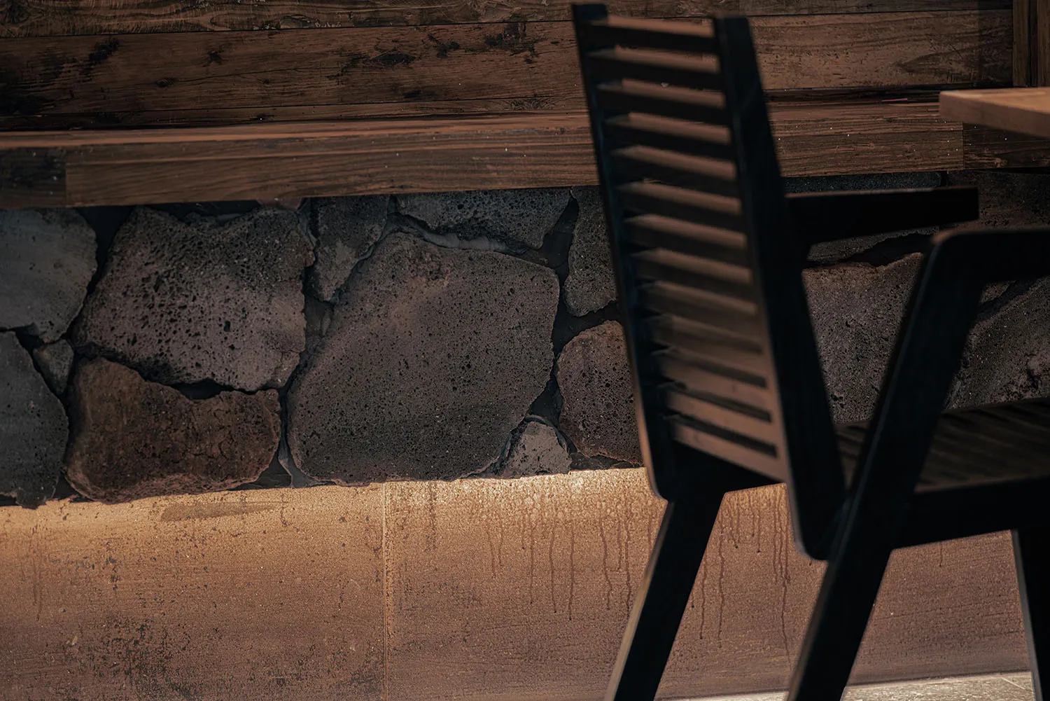 A serene indoor space with a wooden chair next to a stone wall, with a calm atmosphere
