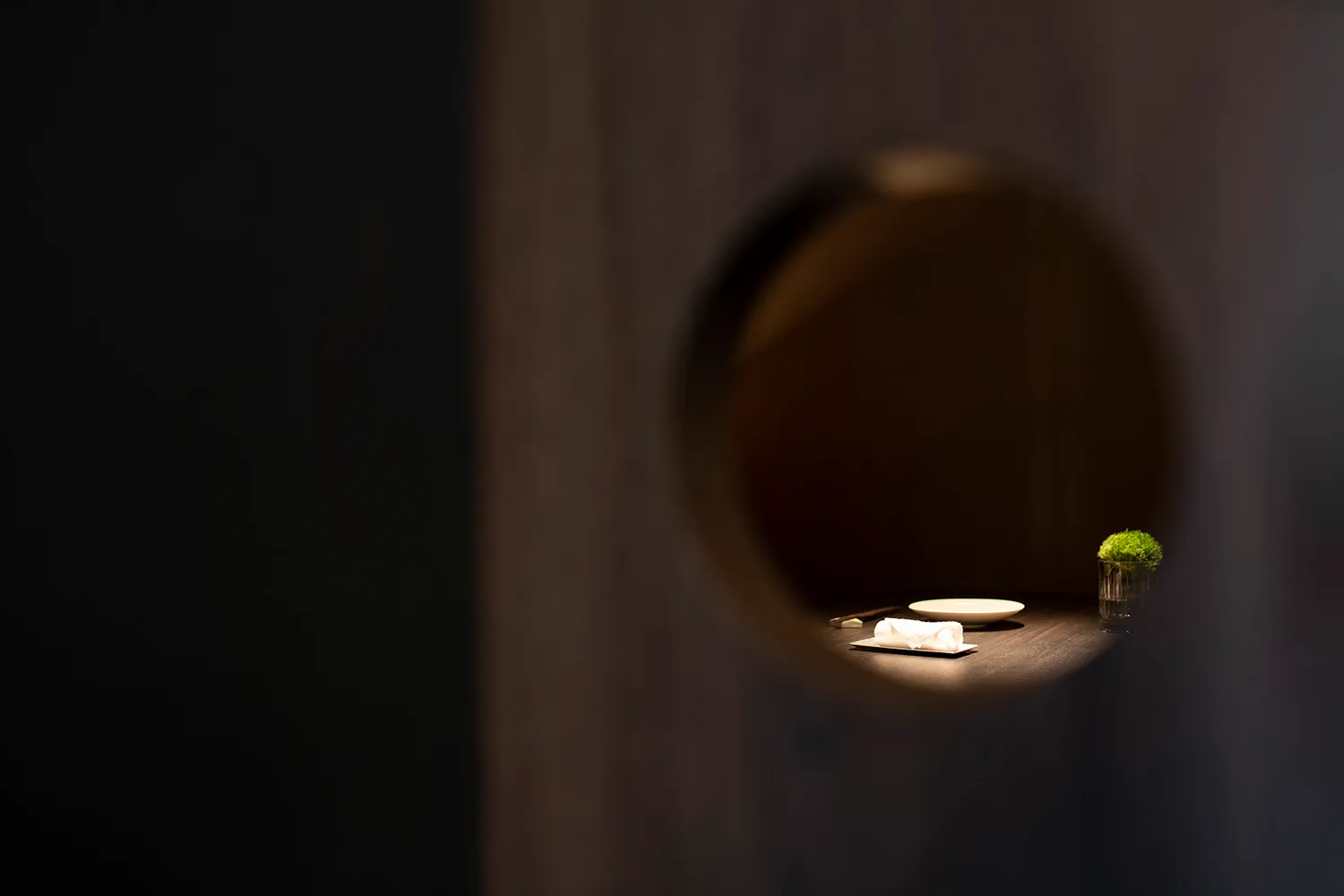 A dimly lit room with a unique wooden door and two white plates on a table