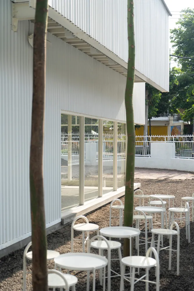 A patio area with white chairs arranged around a dining table, creating a comfortable seating space for socializing and relaxation