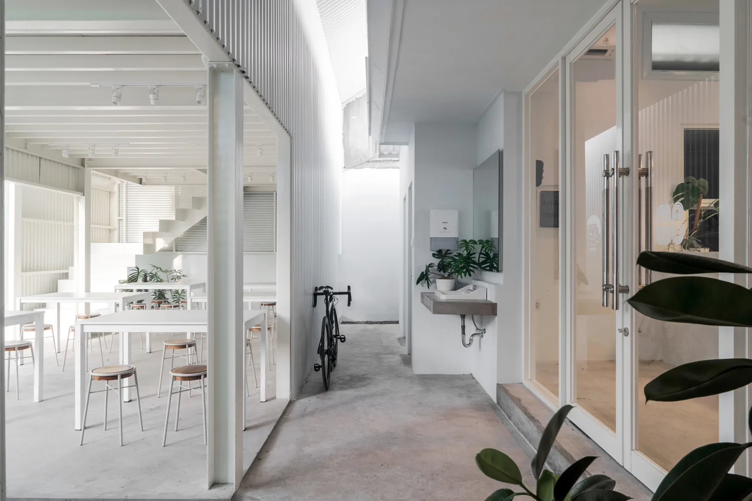 A casual living space with a dining table, two chairs, and a bicycle, set against a neutral background