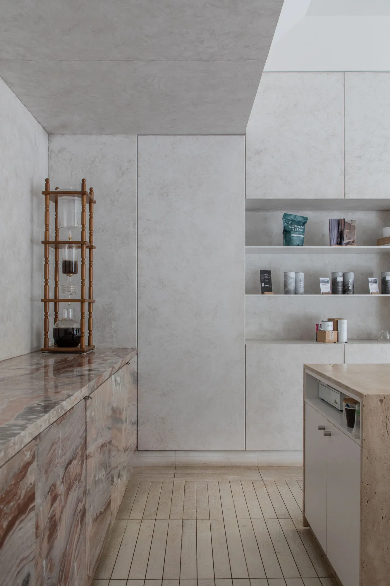 Empty kitchen with white walls and cabinets, featuring a minimalist countertop with several bottles, a cup, and a bowl