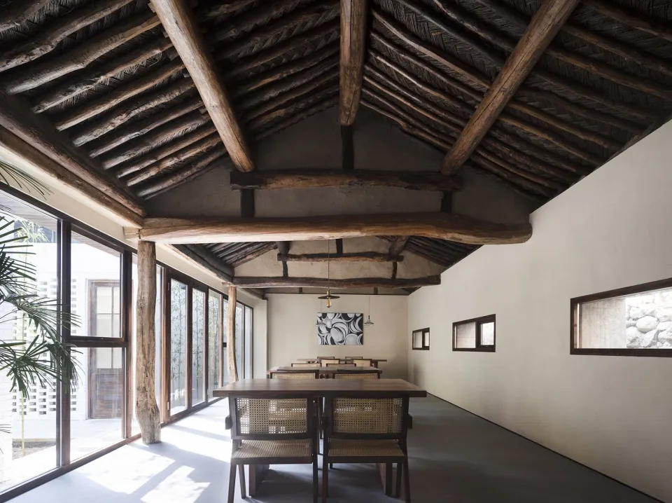 Cozy dining space with a wooden ceiling, a dining table, and four chairs, dimly lit for a warm ambiance