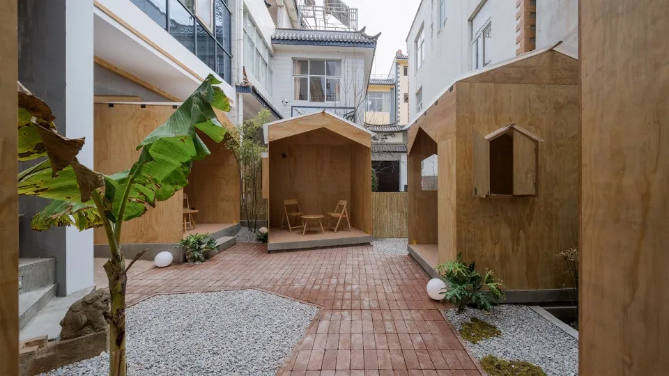 Three small wooden structures in a courtyard area, suggesting a cozy and functional environment