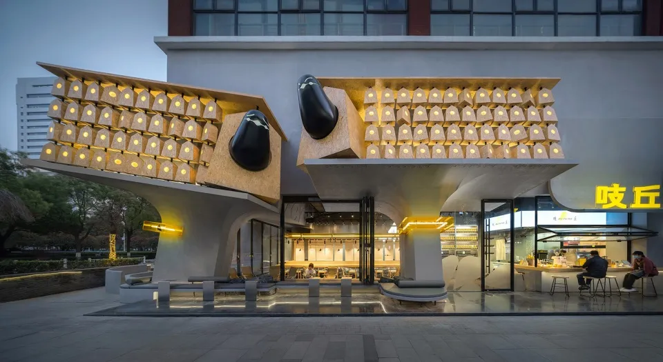剪刀狀設計的現代建築，擁有大型窗戶與座位區，置於中性背景前