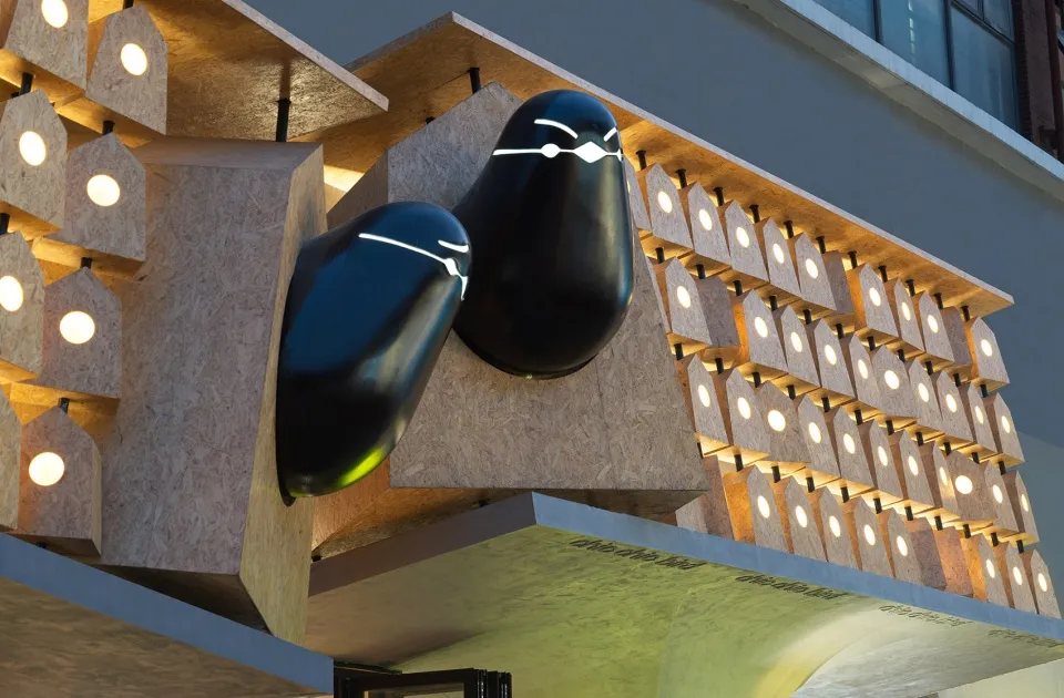 A modern building with two large wooden sculptures hanging off the side, creating a striking visual effect against the backdrop of the building