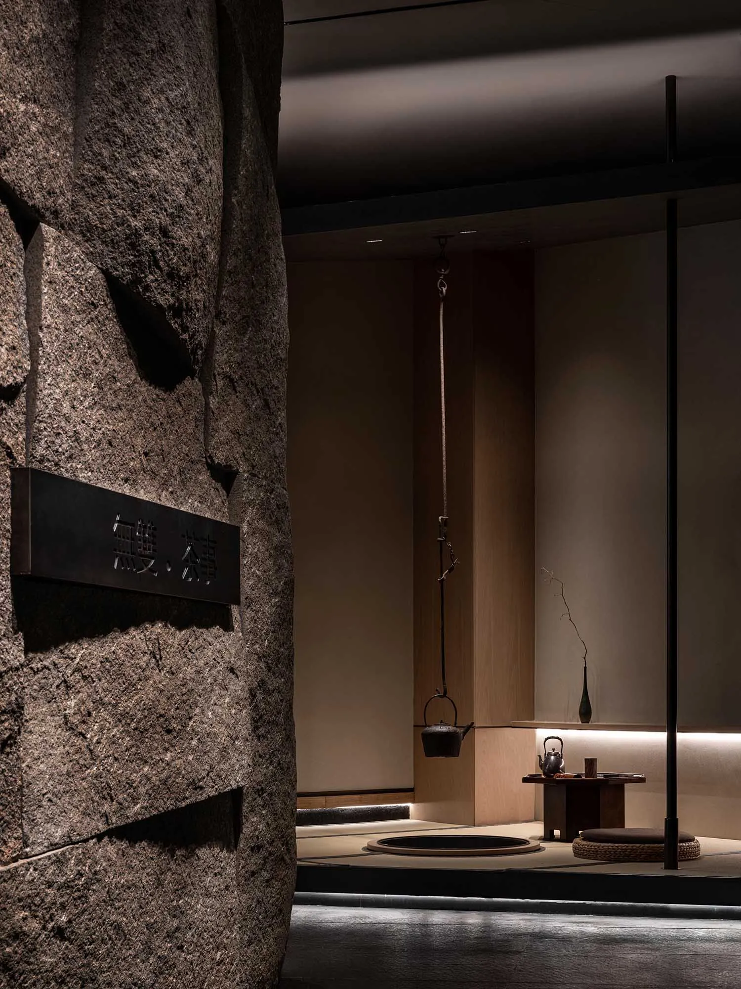 Asian-inspired interior design with a rock wall, wooden table, and serene atmosphere, featuring two cups and a vase
