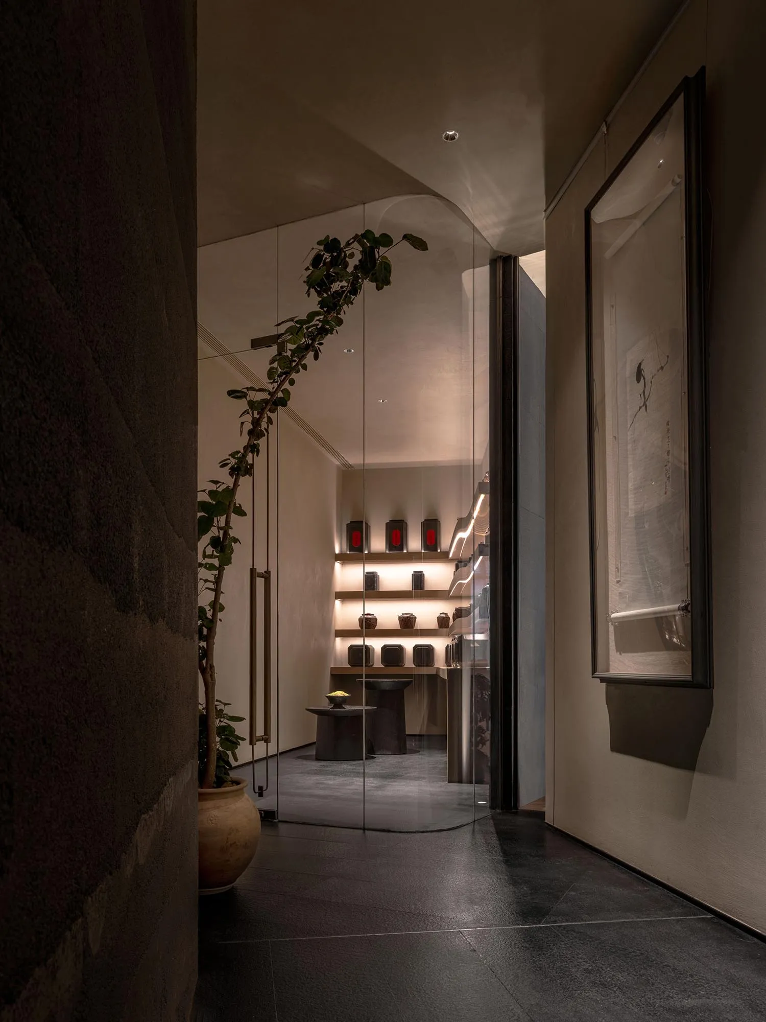 Elegant showroom with glass door, display cases, tables, and cabinets filled with vases, bottles, and other decorative items