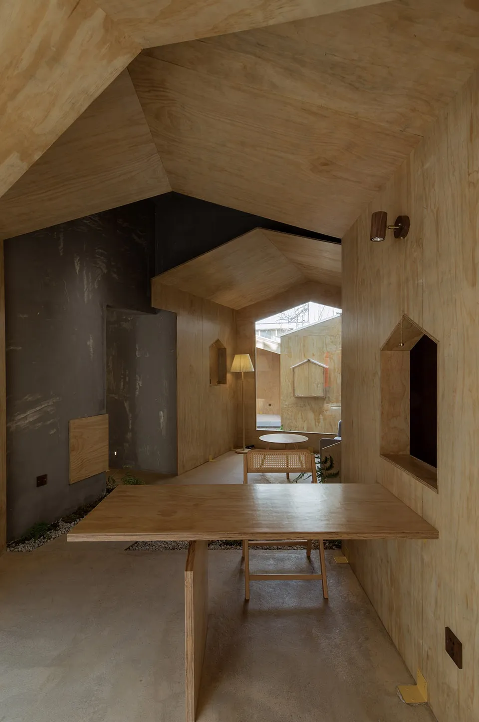 Cozy interior space with wooden walls and ceilings, featuring a dining area, living area, and lamps providing illumination