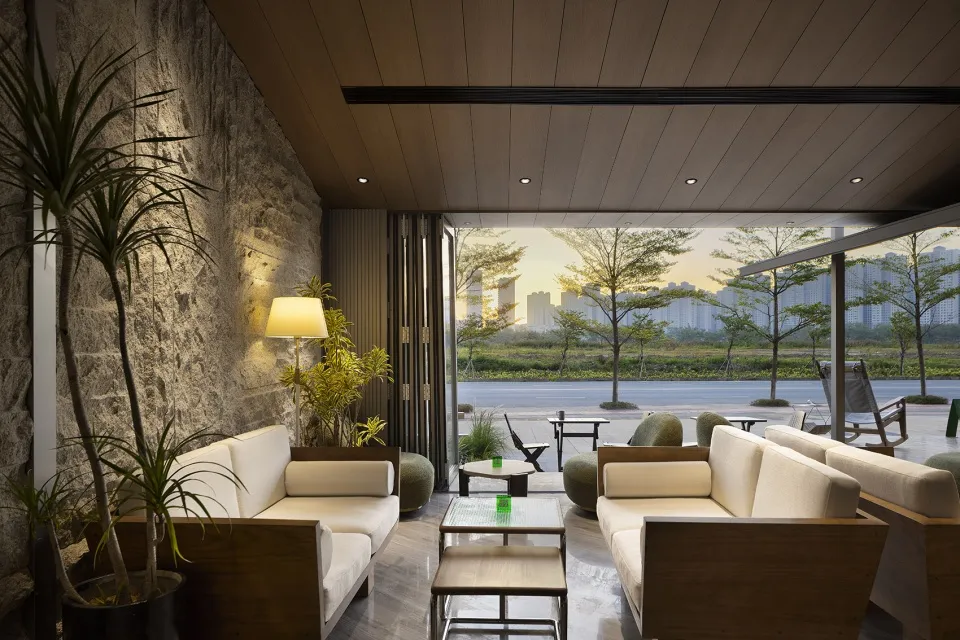Modern living room with white couches, wooden floors, and natural light from a large window