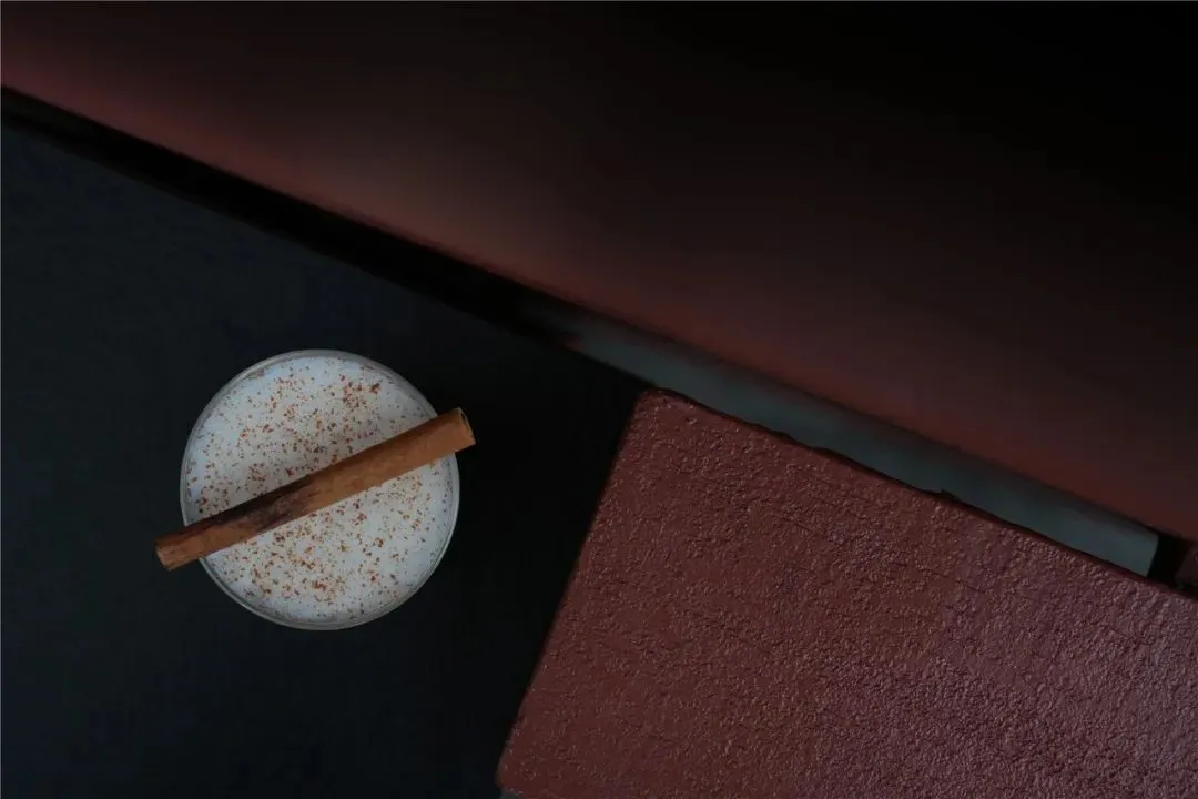 Cozy living space with a couch, table, and warm lighting, featuring a glass of milk and a cinnamon stick
