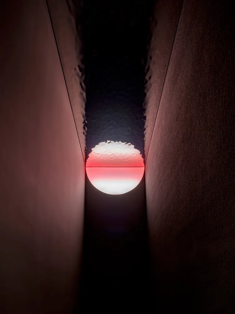 A darkened room with a small window showing a rising sun, creating a striking visual effect
