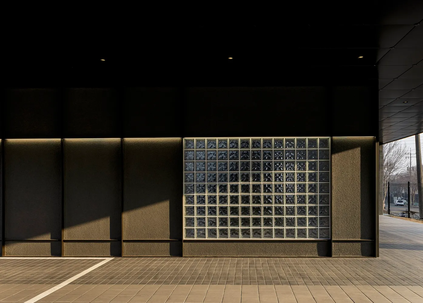 Modern building with a large glass window featuring a checkered pattern, set against a clean and minimalistic backdrop