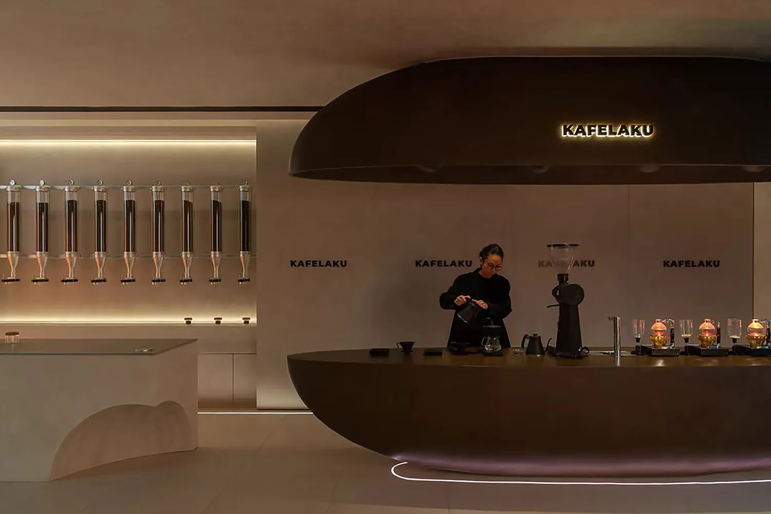 A modern coffee shop interior with a barista preparing drinks behind a counter, surrounded by a circular central feature and concrete walls
