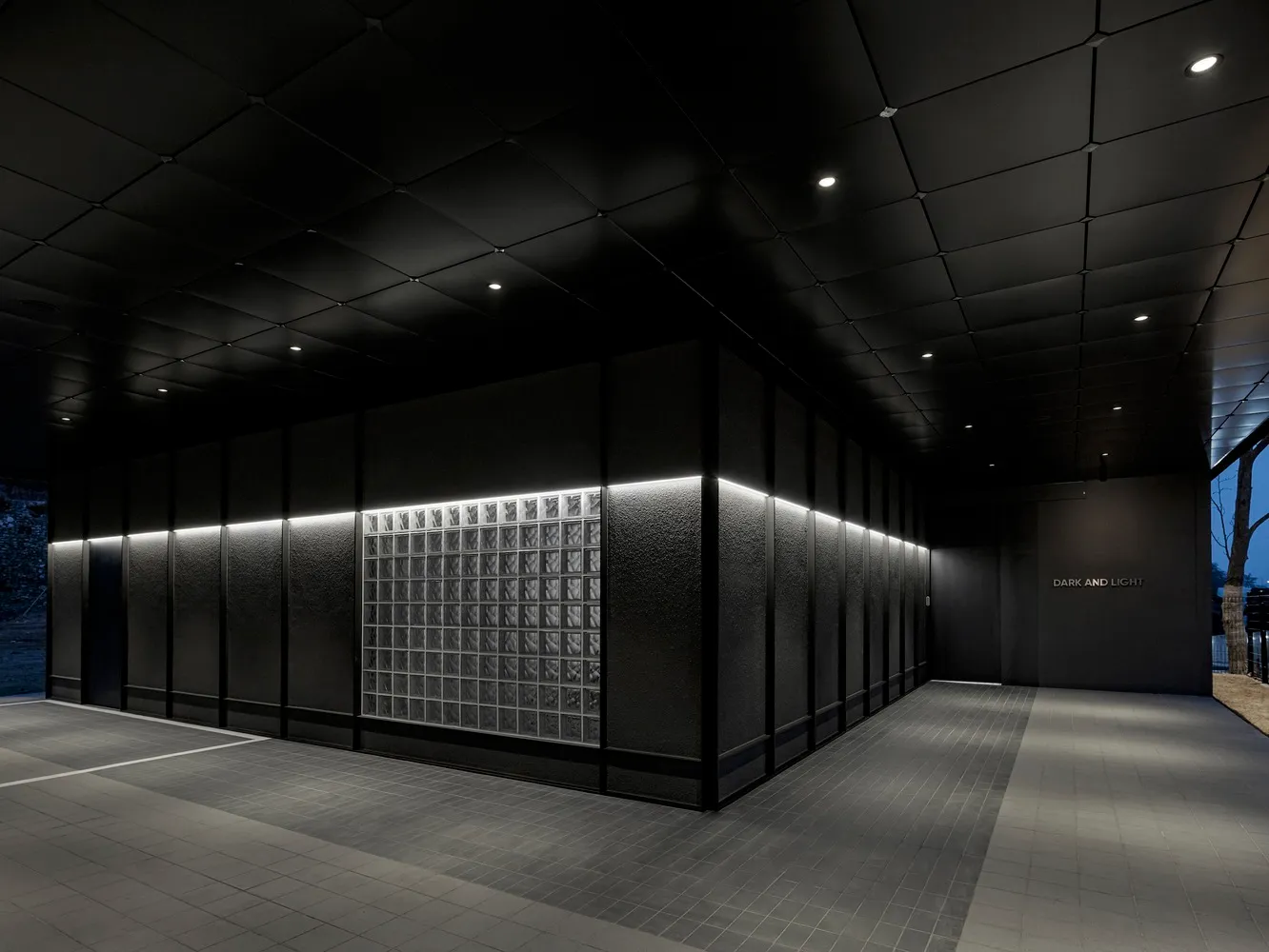 Empty modern hallway with black walls, square windows, and a minimalist atmosphere suggesting a recently renovated or under-construction building