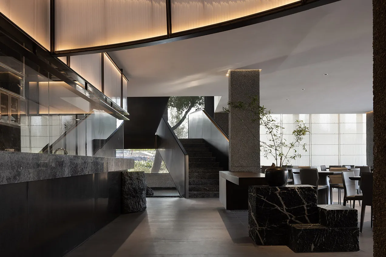 A well-designed interior space with a stone staircase, multiple potted plants, and a sophisticated atmosphere