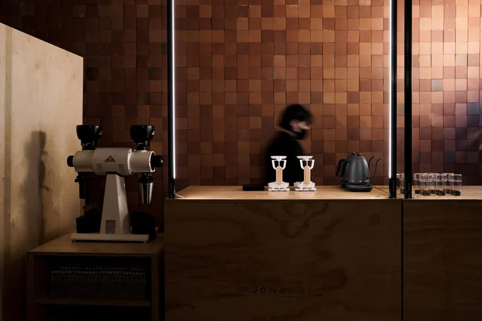 A modern kitchen display featuring coffee pots on a wooden counter, surrounded by cups and bowls, with a well-organized and modern atmosphere