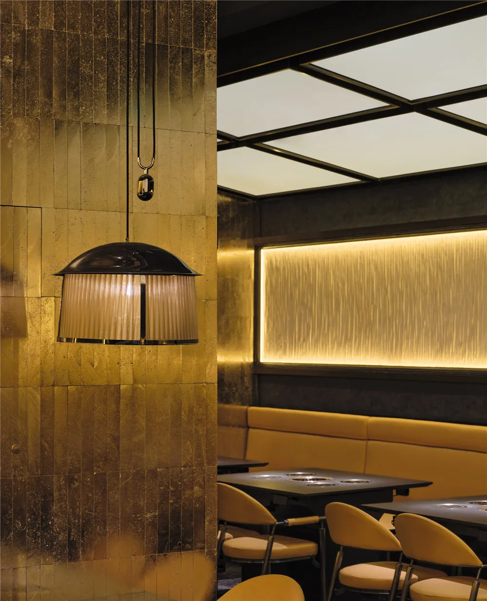 Dining area with multiple tables and chairs in a warm, inviting space with gold-colored walls