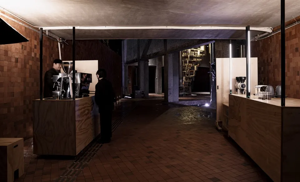 Indoor space with a brick floor, people, bottles, and a cup, creating a casual and social atmosphere