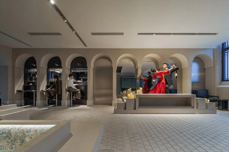 A lively dance hall with a stage, chairs, and wine glasses, set for a social gathering with a dance performance