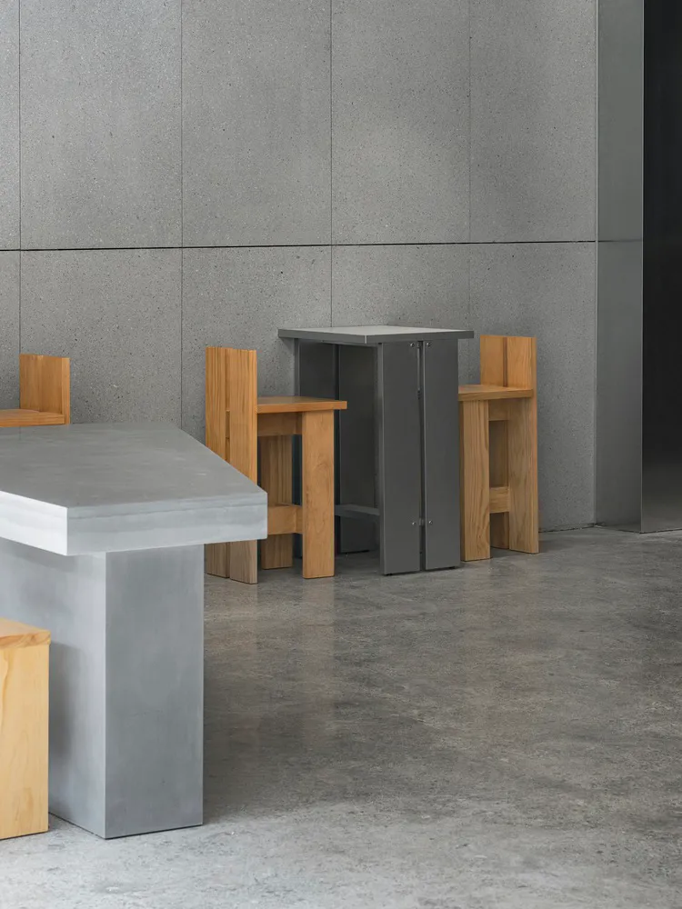 Empty restaurant with grey walls and floors, wooden chairs, and dining tables, with a clean and well-organized atmosphere