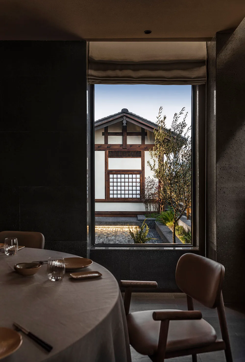 A white Asian-style house with a large window, dining area, and decorative items