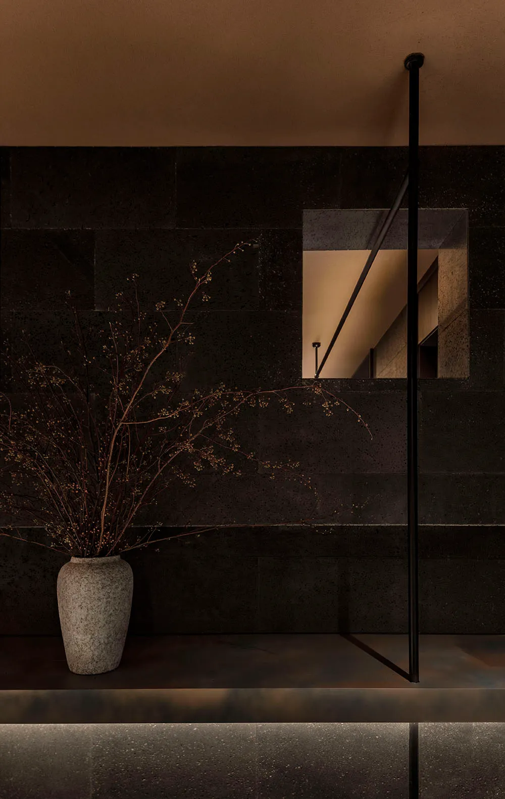 Dark room with black stone walls, a window, and a potted plant, featuring two vases and a somber atmosphere