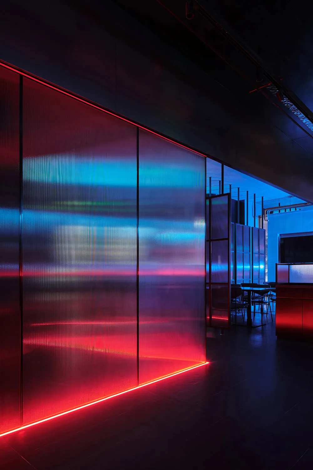 A modern restaurant interior with red walls, two dining tables, and chairs, creating an inviting and stylish atmosphere