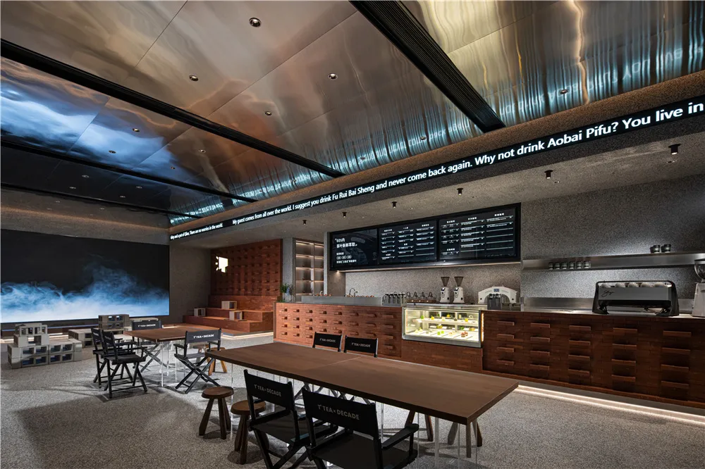 Cozy restaurant interior with wooden floors, a bar, and chairs with black seats, surrounded by tables and beverage cups