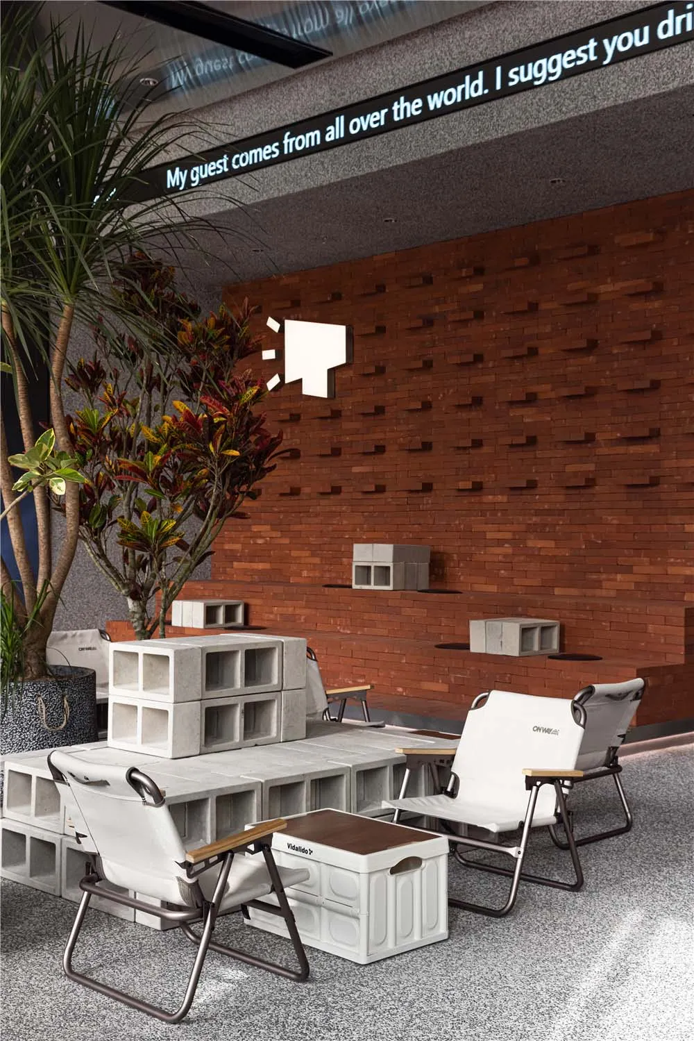 Cozy room with a brick wall, a large tree, two chairs, and a dining table