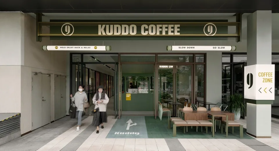 A green and white themed coffee shop with chairs and dining tables, inviting atmosphere, and a woman walking in