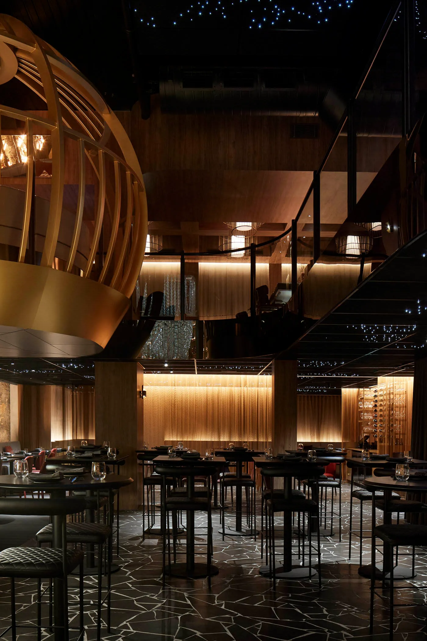 燈光柔和的現代餐廳內部，設有多張桌椅、葡萄酒杯，營造優雅氛圍