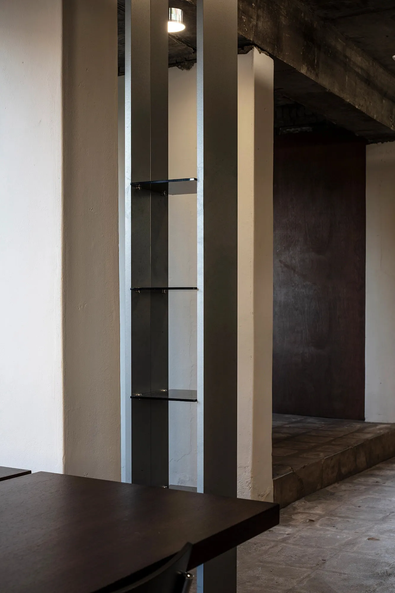 A well-lit interior space with a metal bookshelf mounted on a wall, filled with books of varying sizes and orientations