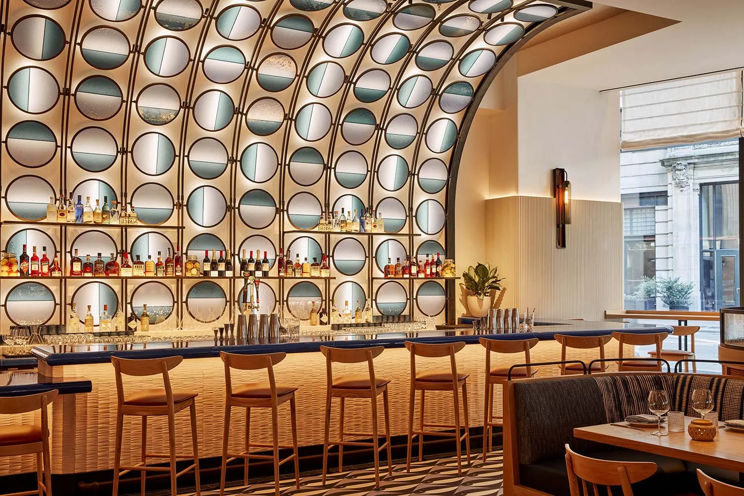A modern bar area with a long counter and multiple chairs, featuring bottles and a sophisticated atmosphere