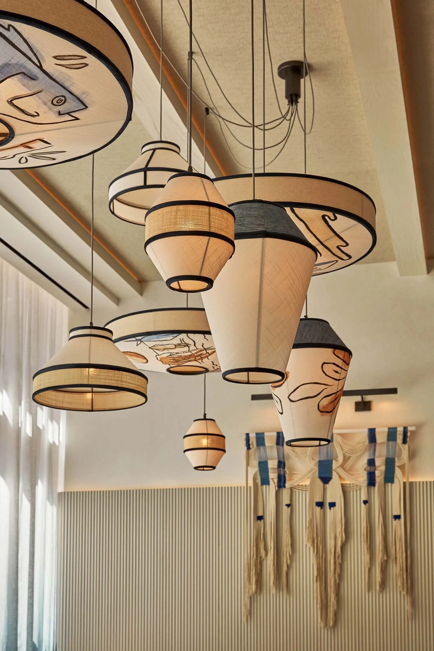 Elegant showroom featuring artistic lighting fixtures made of wood and glass, suspended from the ceiling at varying heights