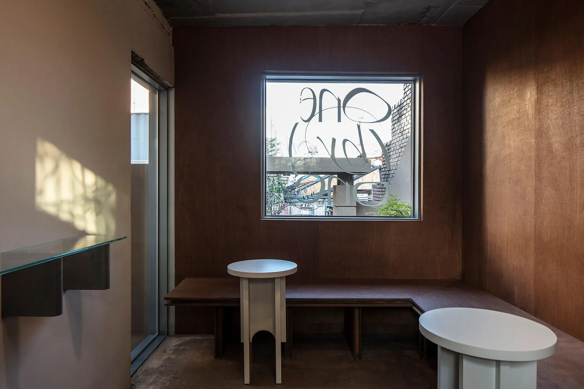 Dining room with wooden walls and floors, featuring a dining table, benches, and a chair, with natural light from a window in the background