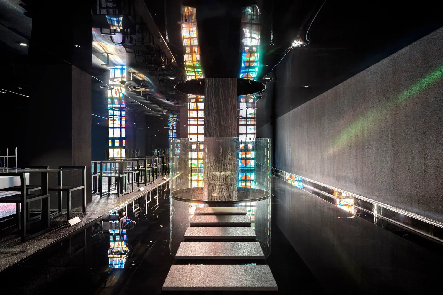 A modern interior space with a glass staircase surrounded by colorful glass panels and metal stairs